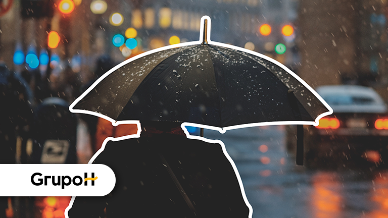 Uma pessoa segurando um guarda-chuva, com um carro ao lado e faróis na rua ligado, representando os dias chuvosos e tensos que podem para alguns financeiramente